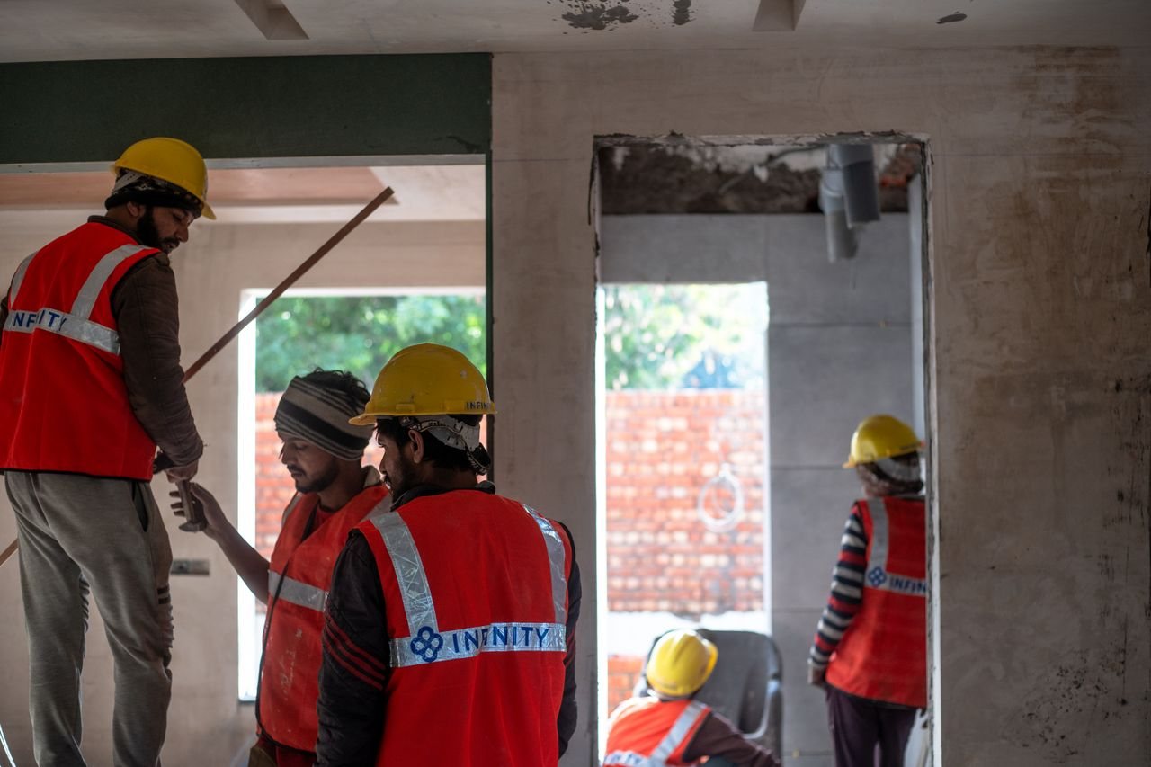 Free Construction workers wearing safety gear at an indoor building site in Delhi. Stock Photo
