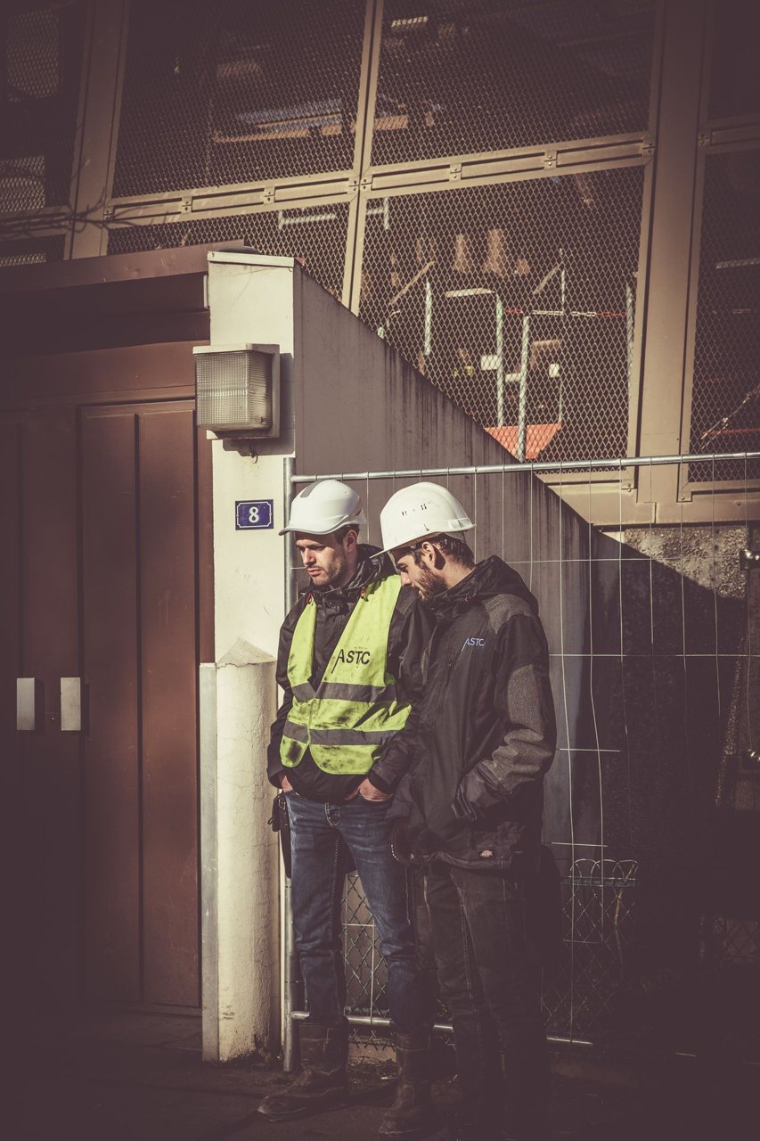 Free Two construction workers in safety gear standing outdoors at a building site, focused on work. Stock Photo